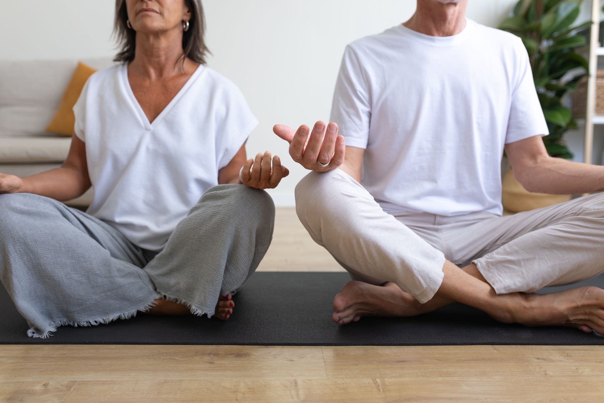 Senior couple meditating together at home on yoga mats